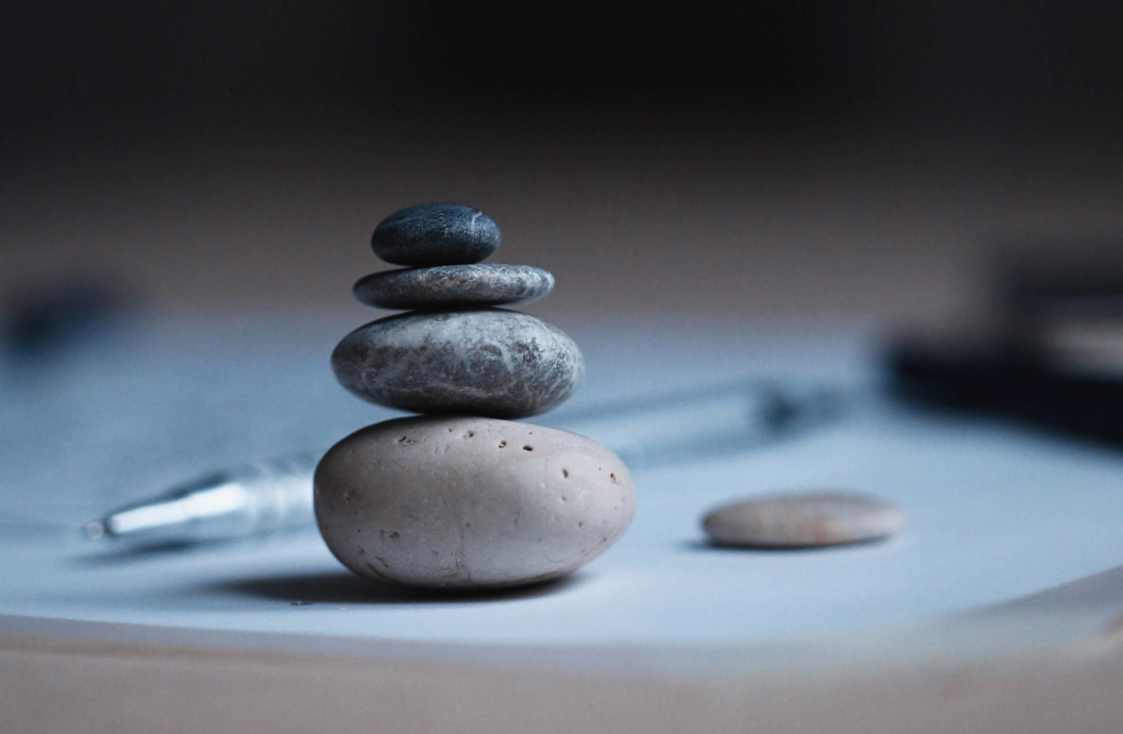 Stones balanced on table with a pen