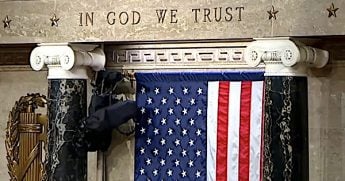 'In God We Trust' is emblazoned above the American flag in the U.S. House of Representatives on Wednesday, April 28, 2021. (Video screenshot)